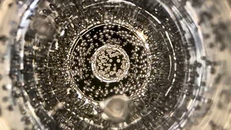 slow motion and extreme close up shot of a glass of champagne bubbles moving up to the surface and exploding