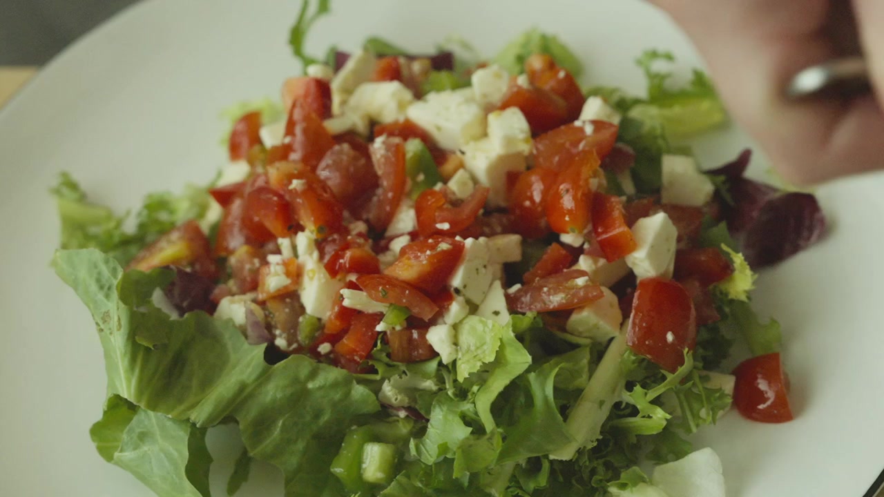 Empratando a salada. Uma mistura saudável e fresca de vegetais e queijo.