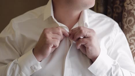 stylish man in jacket fastens buttons, buttoning white shirt preparing to go out near window