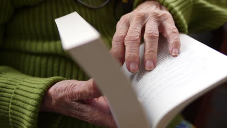 Elderly-individual-using-their-hands-to-turn-the-pages-of-a-book