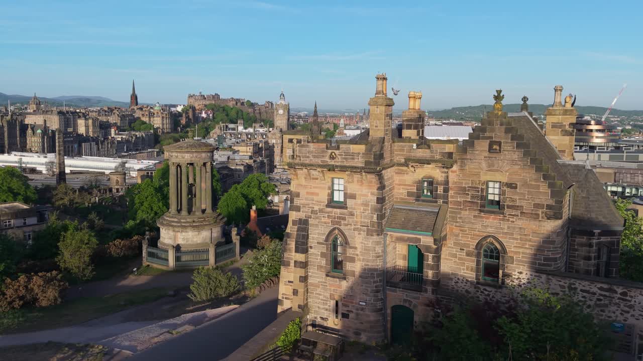 Drone footage reveals the Dugald Stewart Monument in the foreground, with Edinburgh Castle and its clock tower majestically visible behind, showcasing historic landmarks in harmony
