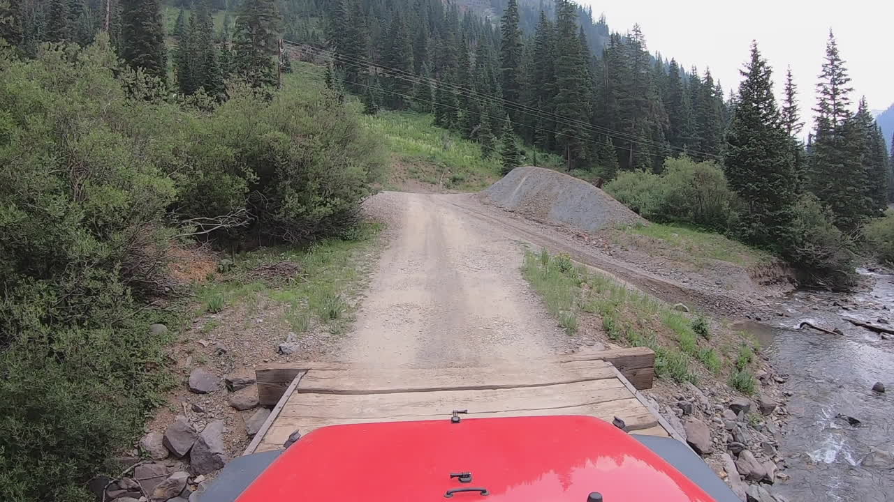 4wd 차량은 우레이 콜로라도 근처 산 후안 산맥에 있는 양키 소년 분지의 스네펠 크릭 위로 나무 다리를 건너고 있습니다.