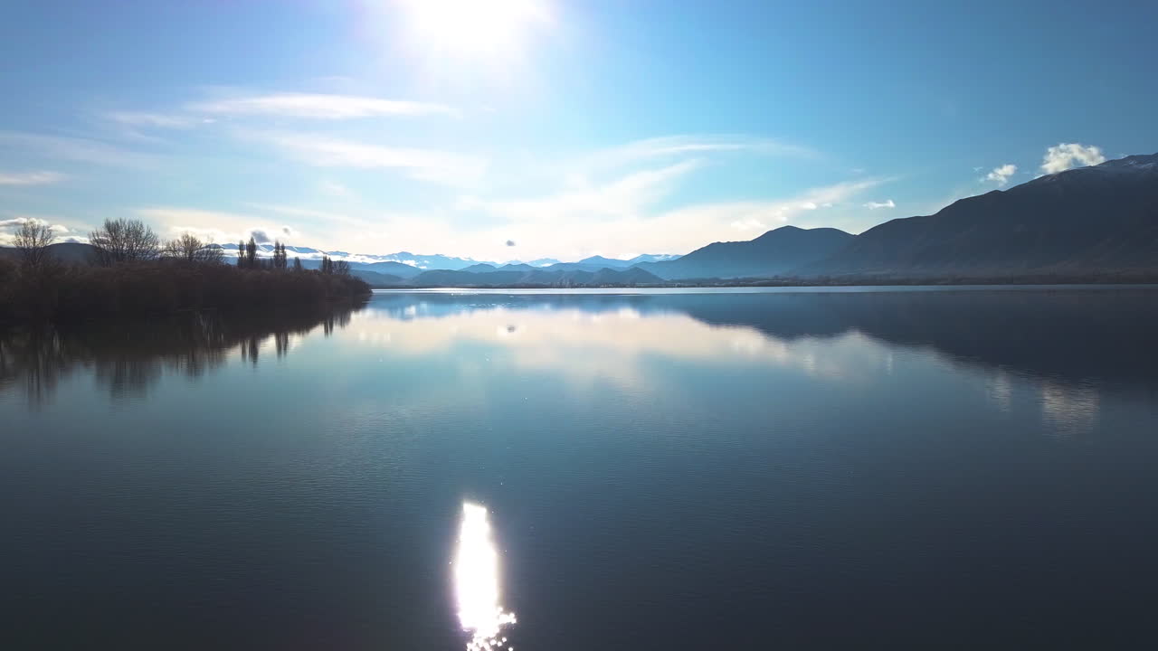 Flying above Lake Benmore, Waitaki valley, New Zealand in a beautiful morning with mountains in front. Beautiful morning scene with serene blue water and sky and birds playing in water.