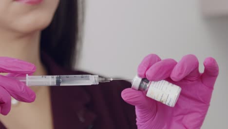 young, hispanic, female doctor filling a syringe from a vial