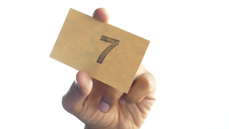 hand holding a card with the number 7