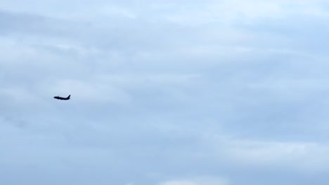 Plane-flying-in-the-distance-cloudy-moody-sky-long-shot-silhouette