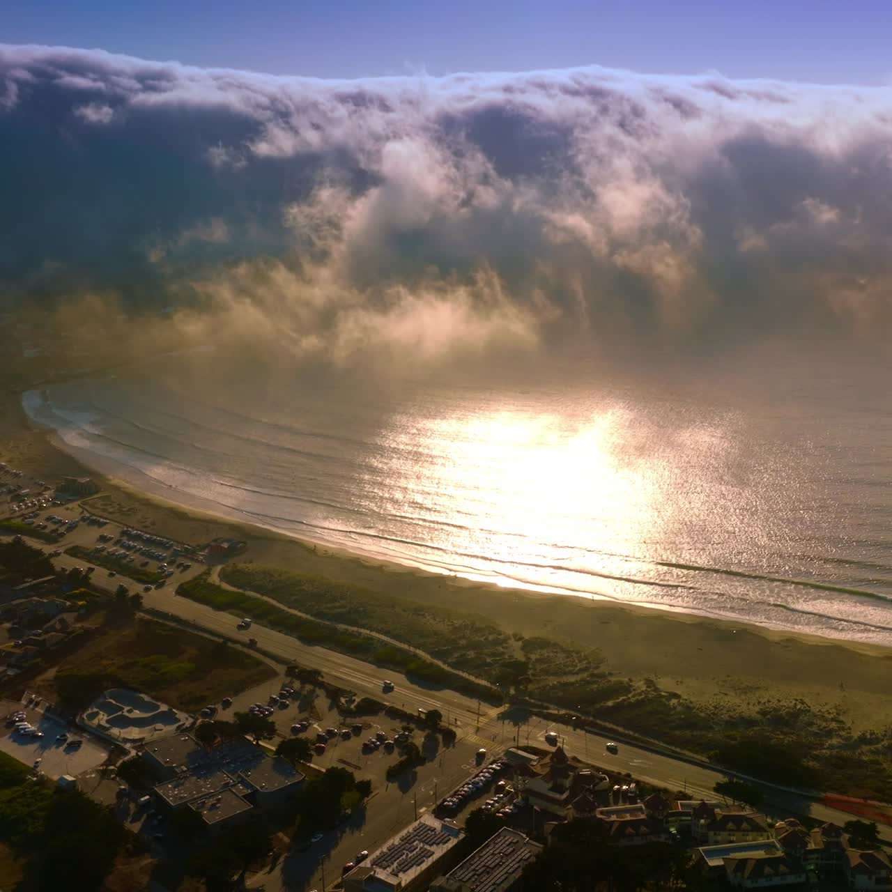 Huge foggy wave approaching the coast of Montara, California, USA from the Pacific. Lovely sunny city at the ocean shore from above
