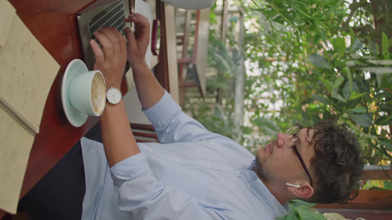 Businessman Having Coffee and Working on Laptop in Outdoor Cafe