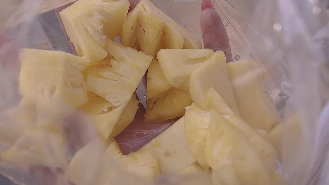 한 사람 이 갈색 대나무 막대기 에 파인애플 조각 을  ⁇ 는다