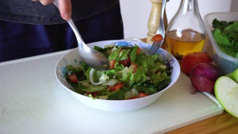 man mixing salad with dressing using spoon and fork