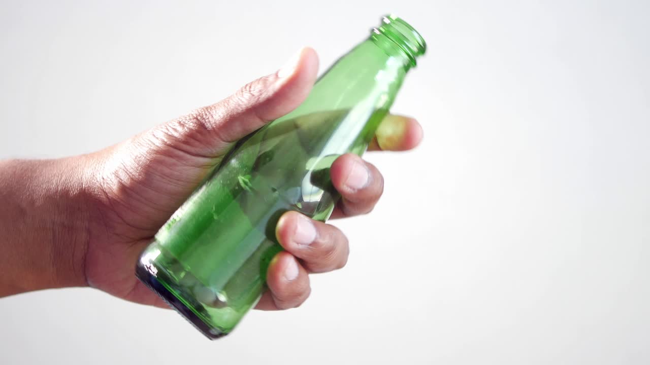 mano con una botella de vidrio verde vacía