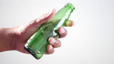 hand holding a green empty glass bottle