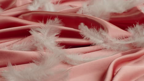 pink satin fabric with white feathers