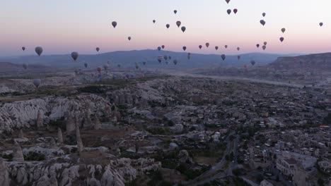 un muñeco aéreo de globos de aire caliente que se eleva sobre los valles rocosos de capadocia al amanecer, revelando impresionantes vistas del paisaje
