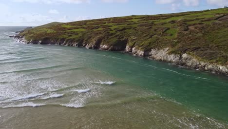 aerial shot cornwall seaside patchwork green and gentle waves pan to horizon