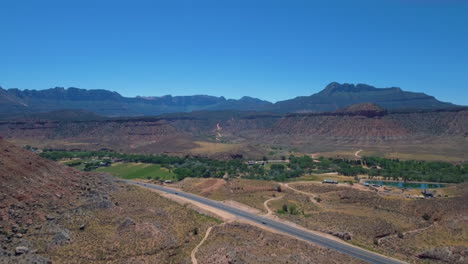 drone shot of road running through mount zion with a mountain range in the background located in southern utah