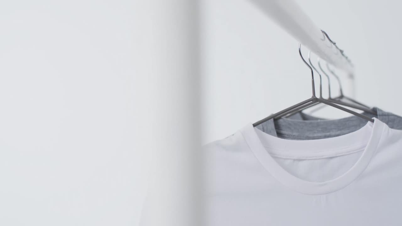 Video of white and grey t shirts on hangers and copy space on white background