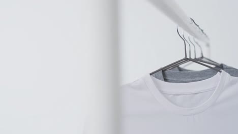 Video-of-white-and-grey-t-shirts-on-hangers-and-copy-space-on-white-background