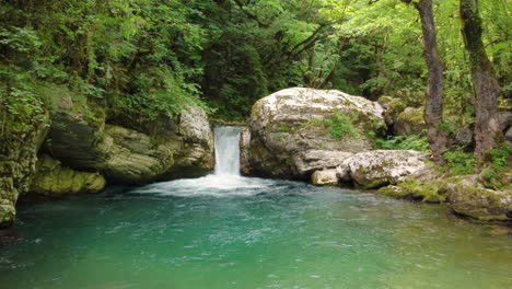 the enchanting scene unfolds as the sun's magical glow illuminates the river in kouiassa waterfall, epirus, where a waterfall cascades amidst the beauty of green forest trees and luxuriant greenery