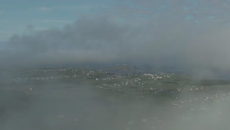 Aerial-flight-in-clouds-moving-above-rooftops-in-rural-village-on-Magdalen-Island