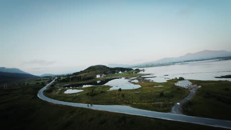 Filmische-FPV-Drohnenaufnahme,-Stabilisiert-Von-Den-Lofoten-Aus,-Während-Drei-Wanderer-Während-Der-Blauen-Stunde-Auf-Einer-Einsamen-Landstraße-Fliegen