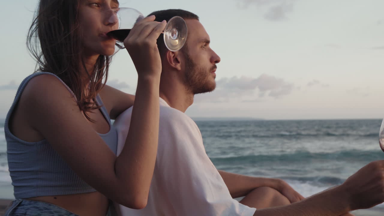 바람이 불는 해변에서 와인을 마시는 커플