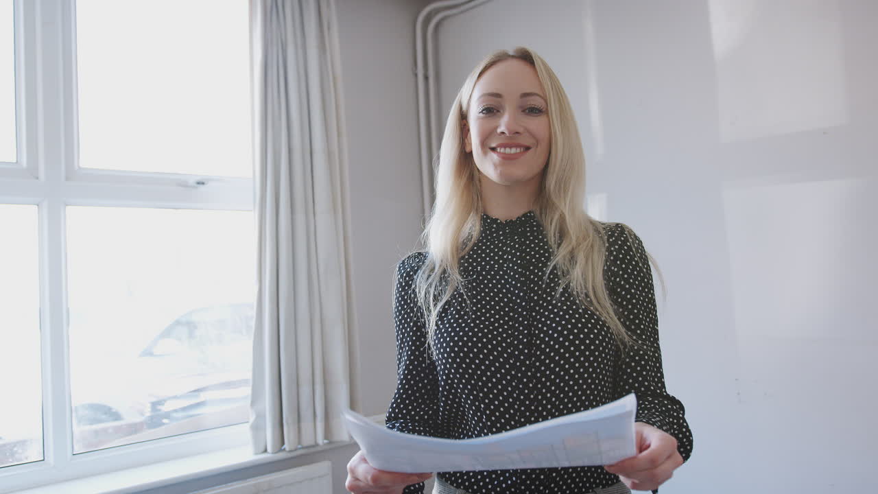 Portrait Of Female Realtor Looking At House Details In Property For Sale