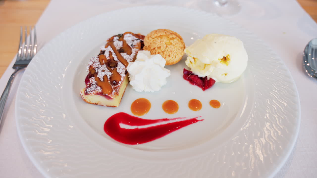 Close up of a dessert plate with a tart, a cream puff, ice cream, and sauces