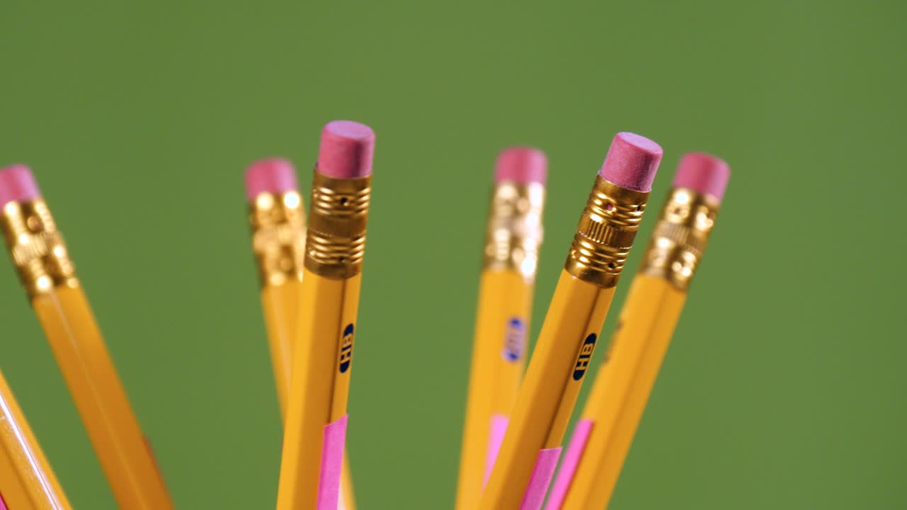 close up de lápices de borrador amarillos girando en un fondo verde
