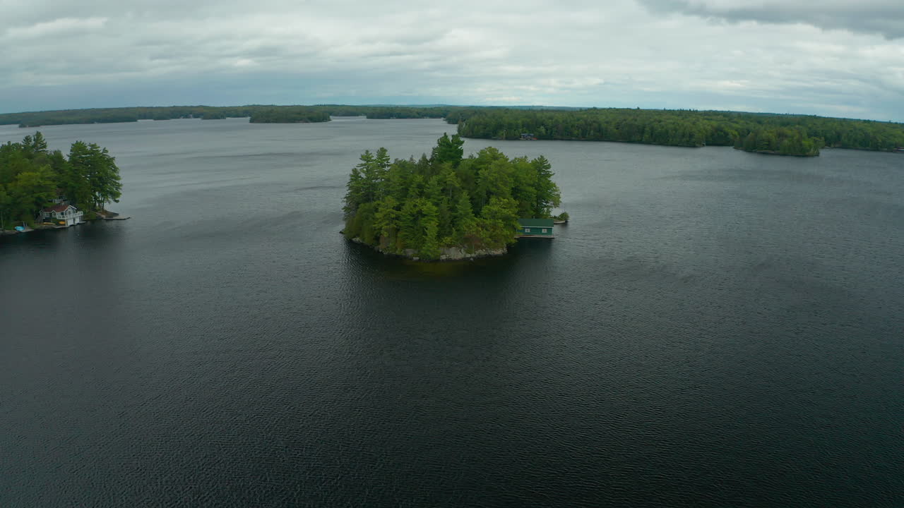 vista aérea volando sobre una pequeña isla aislada con una cabaña en medio de un lago