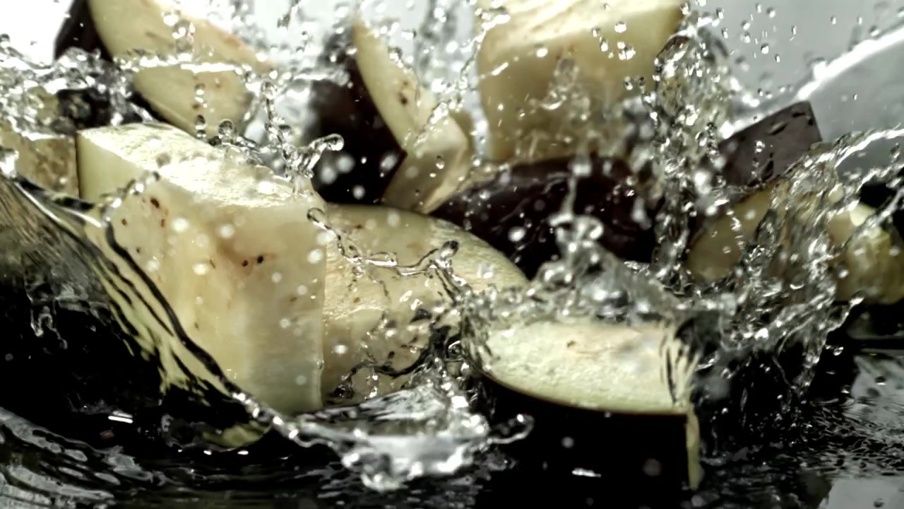 Chopped Eggplant Pieces Splashing into Water in Slow Motion