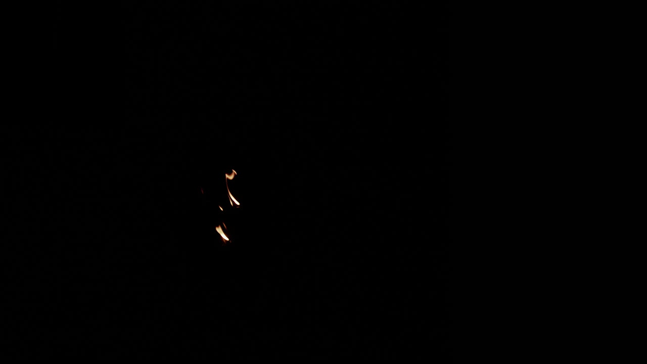 Small group of slow motion flames burning on left of screen that slowly burn out.