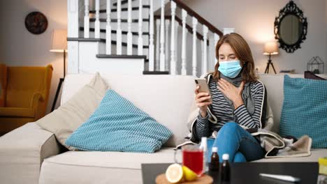 ill woman wearing a surgical mask and sitting on the sofa