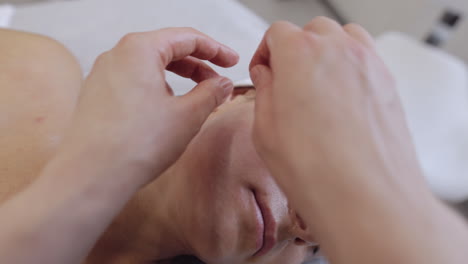 코스메톨로지 테라피스트는 여성이 휴식을 취하는 스파에서 손으로 얼굴 마사지를 할 수 있습니다.