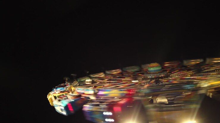 Ruota panoramica illuminata in rapido movimento in un parco divertimenti di notte