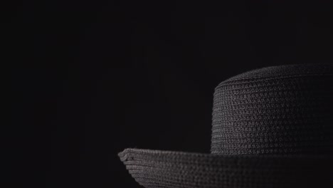 Wide-brim-woven-straw-hat-on-a-spinning-display-and-black-background-with-available-copy-space