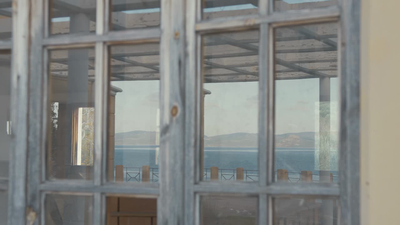 reflejo de la costa turca en una ventana de un edificio griego abandonado