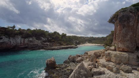 volando a lo largo de la costa mallorquina y a través de la entrada rocosa a una playa aislada