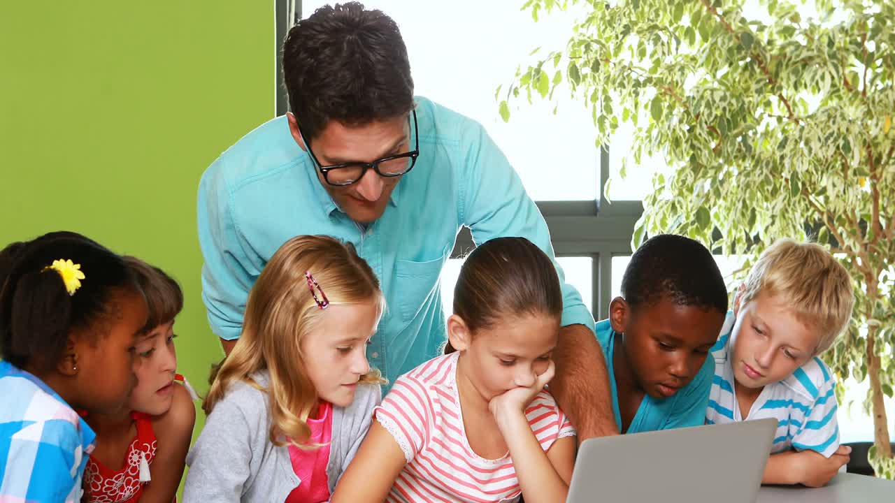 el maestro y los niños usando la computadora portátil en el aula