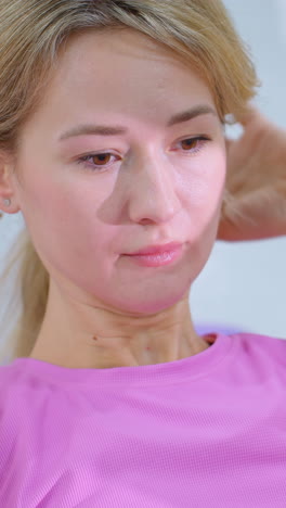 분홍색 운동복을 입은 여성이 체육관에서 보라색 매트 위에 머리를 뒤로 한 채 코어 운동을 수행하여 피트니스 루틴에서 집중과 노력을 유지합니다.