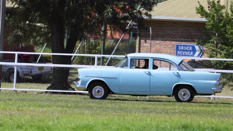 classic car driving by a fenced area