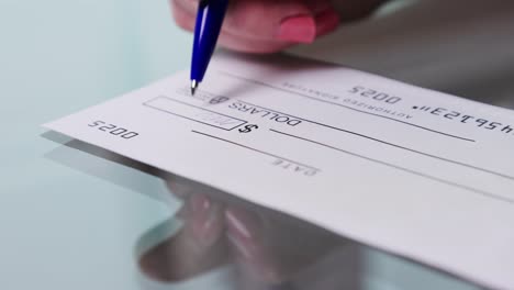 business woman hand signs and filling bank check for one thousand 1000 dollars