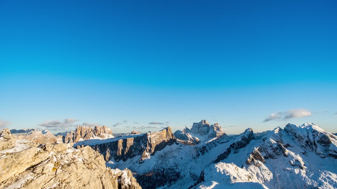 Cielo azzurro e nuvole in movimento sopra la cima innevata e ghiacciata delle montagne durante l'ora d'oro - Filmato time-lapse