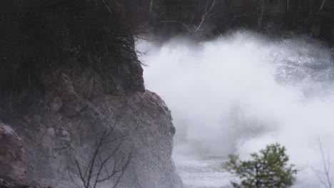 Rough-waves-during-a-storm-crashing-onto-rocky-coastal-cliffs,-slow-motion