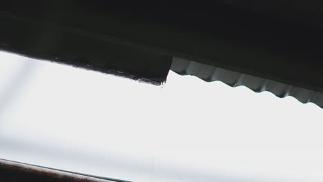 rain dripping from above overflowing gutter on house roof