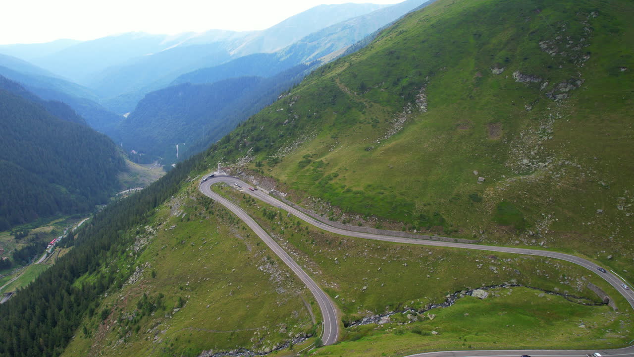 Raining in the Transfăgărășan road surrounded by green valleys. Aerial