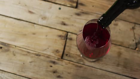 red wine pouring into glasses over wooden surface with copy space