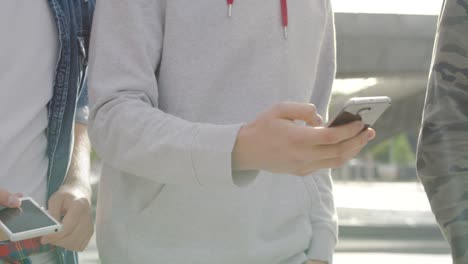 three male friends using smart phone outdoors