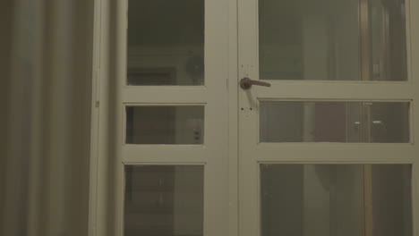 a traditional white wooden door with glass panes and a vintage handle, suggesting a historical or public building