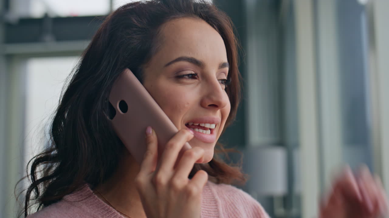 Smiling woman talking mobile phone at home closeup. Relaxed girl looking window